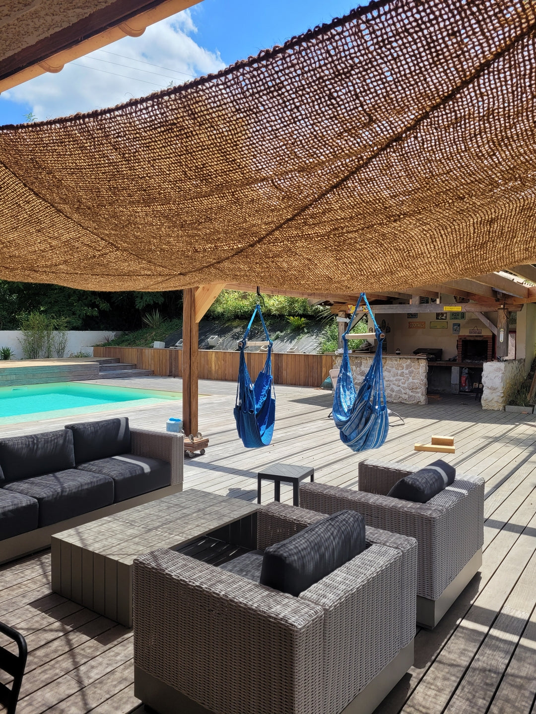 Toldo de fibra de coco sobre una zona de descanso junto a la piscina