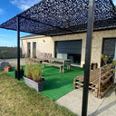 Red de camuflaje negra sobre una pérgola en una terraza con césped