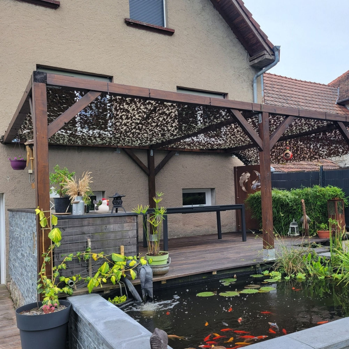 Red de camuflaje militar sobre una pérgola de madera junto a un estanque