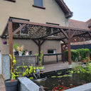 Red de camuflaje militar sobre una pérgola de madera junto a un estanque