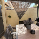 Red de camuflaje triangular gris como toldo sobre una mesa de terraza