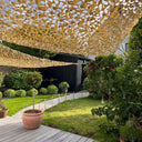 Redes de camuflaje triangulares beige como toldos en un jardín