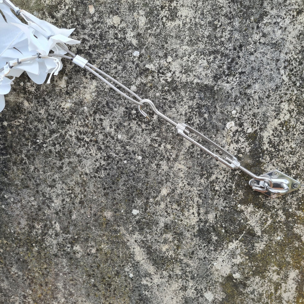 Tensor y gancho de fijación en una pared de piedra con esquina de red de camuflaje blanca