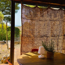 Cortina de fibra de coco junto a una ventana con mesa y lámpara