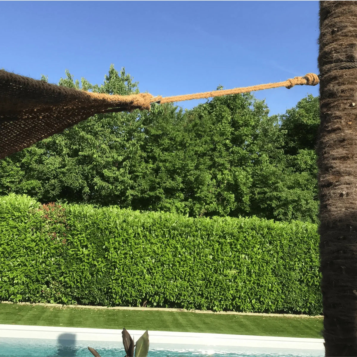Cuerda de fibra de coco sujetando un toldo de coco junto a una piscina